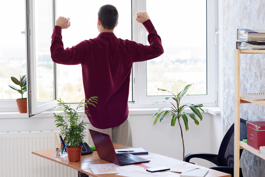 Office worker does gymnastics standing by the window