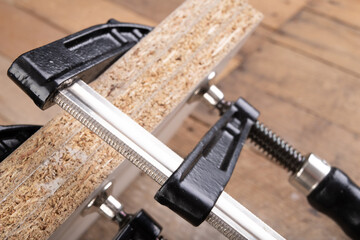 Carpentry clamp used for gluing wood. Small carpentry work in a home workshop.