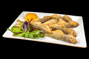 Gourmet Fried Trachurus with lemon and arugula on a plate, isolated on black background