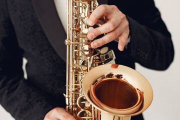Man in a studio. Guy in a black suit. Musician with saxophone.