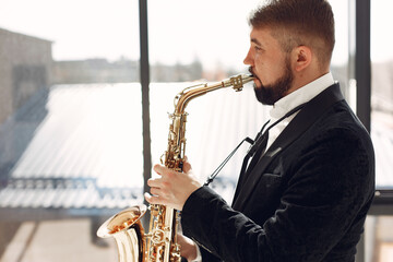 Man in a studio. Guy in a black suit. Musician with saxophone.