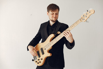 Obraz premium Man in a studio. Guy in a black suit. Musician with a guitar.