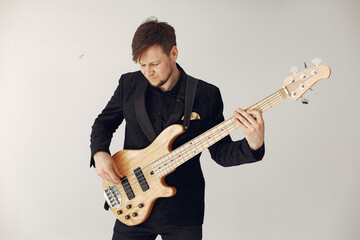 Obraz premium Man in a studio. Guy in a black suit. Musician with a guitar.