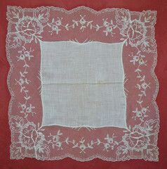 Vintage linen and lace handkerchief on a rose background suitable as a frame or background