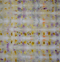 Fabric cloth background with pattern made from natural dyes in purple, yellow, gold, and rust