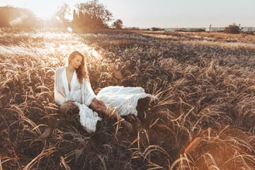 a girl in a field at sunset in a white dress