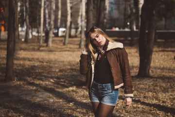 Beautiful girl with long hair walks and poses in a city park in early spring or autumn