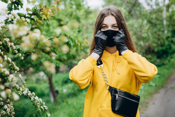 Girl wearing stylish handmade protective face mask posing on street. Fashion during quarantine of coronavirus outbreak.