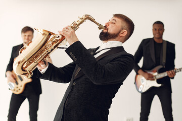 Fototapeta na wymiar Music band in a studio. Guy in a black suit. Musician with saxophone.