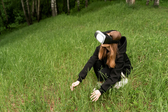 girl in virtual reality glasses touches the grass raising her head to the top - Powered by Adobe