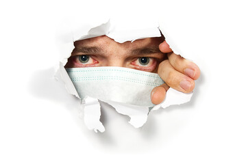 Man in medical mask peeping through hole on paper. Male Eye looking through hole. Isolated on white...