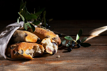 Traditional italian puccia breads with black olives in a cotton bag, made in Salento, Puglia on a wooden background
