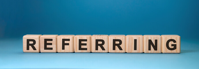 Referring - text concept on wooden cubes with gradient blue background