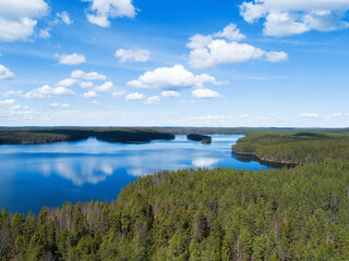 Fototapeta na wymiar Sunny landscape in Finland with beautiful lake, forest and blue sky with some clounds. Amazing scandinavian nature, travel and hiking tourism destination.