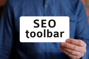 Seo toolbar - text on a white sign in the hand of a man in a blue shirt