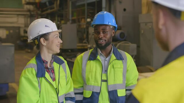 Three diverse technicians in safety gear gesturing high-five and smiling