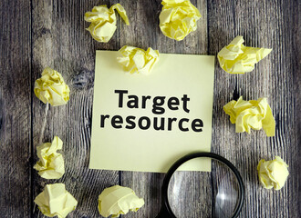 Target resource - text on yellow note sheets on a dark wooden background with crumpled sheets and a magnifying glass