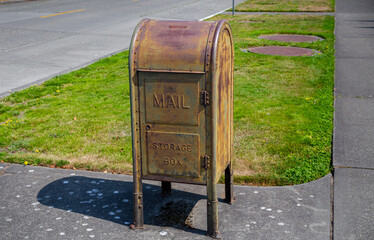 A vintage weathered Postal Service Mailbox storage box on a sunny day with grass in the background