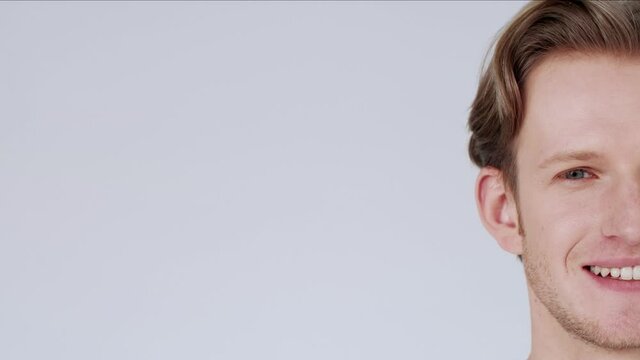 Handsome young man, looking at camera with happy, carefree expression, smiling. White background. Close-up