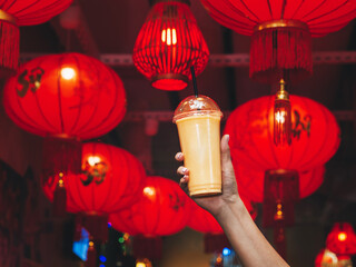Traditional chinese red lanterns. Plastic glass of freshly squeezed juice. Mango shake. Food Festival. Hand holds a glass. Vegetarian drink. Useful food. Gastronomic journey. Asian traditions