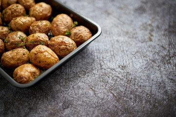 Homemade roasted whole potatoes in jackets. With butter, rosemary and thyme. Served in metallic dish