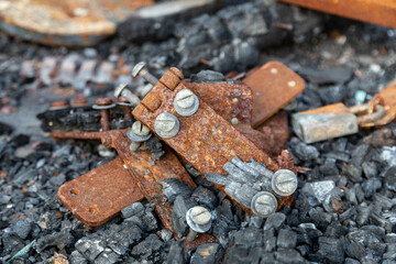 A close-up view of a pile of rusted hinges and fire damaged,chard rubble 
