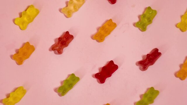 Colorful gummy bears on pink background. Stop motion jelly candies. Sweets industry 