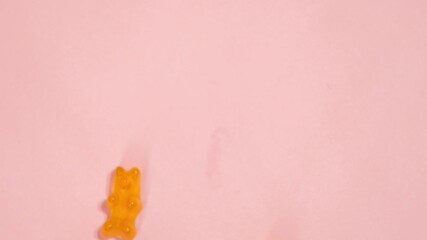 Colorful gummy bears on pink background. Stop motion jelly candies. Sweets industry - Powered by Adobe