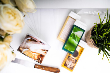 Liposoluble wax cartridges and tropical leaves on white background. . Cosmetology and beauty concept. The concept of depilation and beauty is sugar paste or hair removal wax.