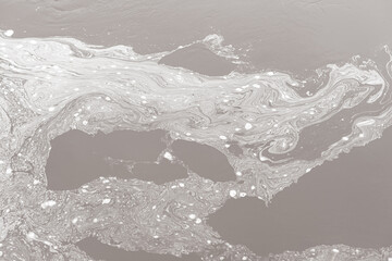 white pattern on a gray background formed by foam on the river due to water pollution