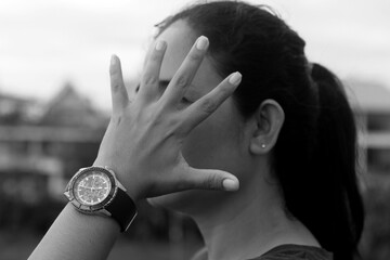 Hand stop gesture on young woman face with watch in hand in black and white background. No or stop...
