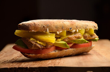 Meat sandwich with avocado, tomato, mayo, chilli in a baguette