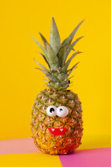 pineapple fruit with funny eyes on a yellow pink background
