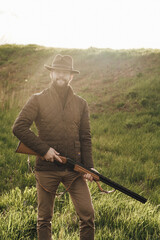 Vintage hunter walks. Rifle Hunter Silhouetted in Beautiful Sunset or Sunrise. Hunter aiming rifle...