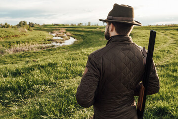 Vintage hunter walks. Rifle Hunter Silhouetted in Beautiful Sunset or Sunrise. Hunter aiming rifle...
