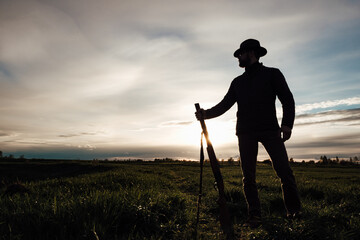 Vintage hunter walks. Rifle Hunter Silhouetted in Beautiful Sunset or Sunrise. Hunter aiming rifle in swamp and field