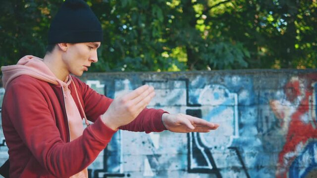 Trendy cool young man is showing some dancing hands elements. Imimtating waves. Copy space. Close up. 4K.