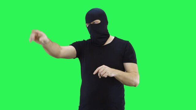 A masked man manages the situation, showing with his hands what to do.Balaclava.Green screen background.