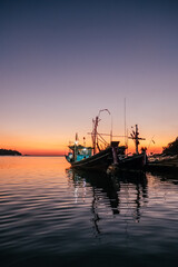 Traditional thai fisghing boats in the sea at twilight in Thailand