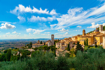 Fototapeta na wymiar Veduta della città di Assisi, Umbria, Italia, città natale di San Francesco di Assisi e luogo di pellegrinaggio, con cielo blu e nuvole bianche