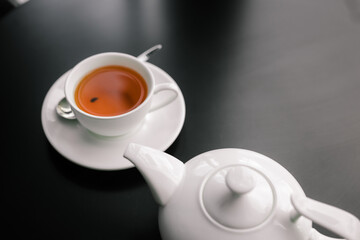 a white teapot with a white Cup on a black table