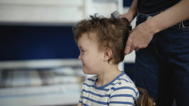 Mom combes a beautiful, curly, smiling son.