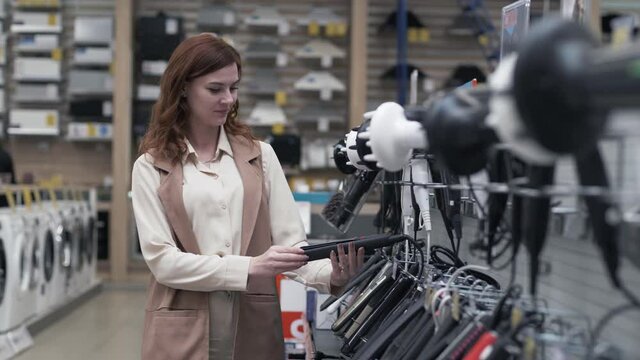 retail store, pretty young female shopper choosing hair tools on store shelves during a sale