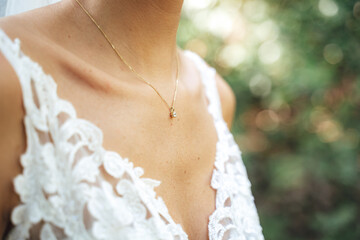 Close up of caucasian bride's chest in white lace wedding dress. Neckline decorated with golden...