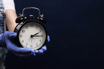 Hands in protective gloves holding medical alarm watch. The concept of time to the end of the pandemic corona virus