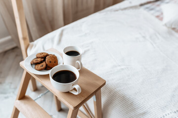 Breakfast in bed. Hot coffee with oatmeal cookies with chocolate on a wooden tray.