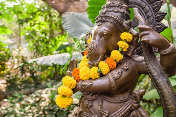 Bronze Ganesha statue with marigold flowers in the tropical garden