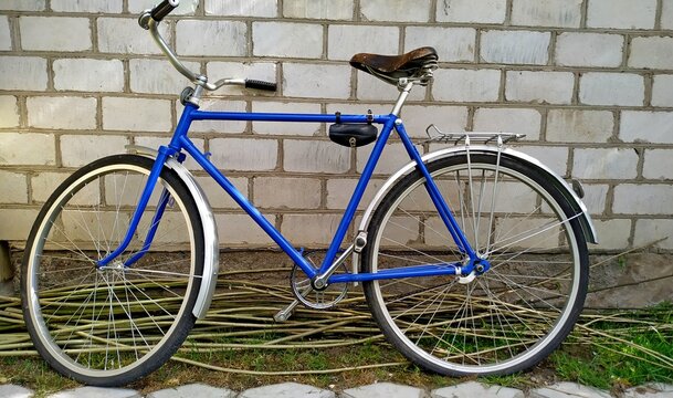 Blue vintage bicycle on a white brick wall background. Mobile photo