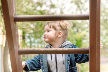 Obraz premium Active little girl on playground.Summer in the park. seeds on a swing. plays children's games, runs and jumps. carefree childhood.