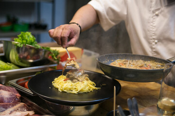 the pasta is served by the chef on a plate to serve to the customer
